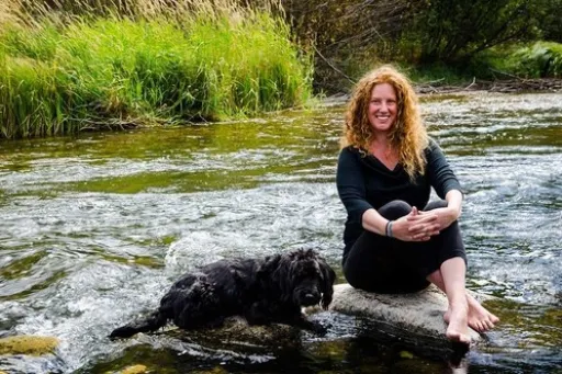 Business owner poses by the river with their dog
