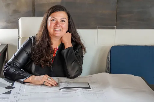 Woman business owner sits at their desk with blueprints